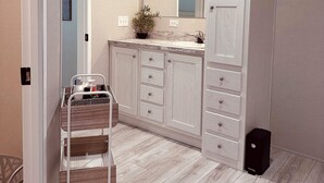 A modern bathroom with a wooden vanity, a large mirror, and a small plant on the counter. - K & M Suite is a brand-new home in a peaceful, quiet neighborhood. (Wabash)