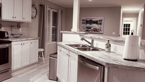 A modern kitchen with white cabinets, a marble countertop, and stainless steel appliances. - K & M Suite is a brand-new home in a peaceful, quiet neighborhood. (Wabash)