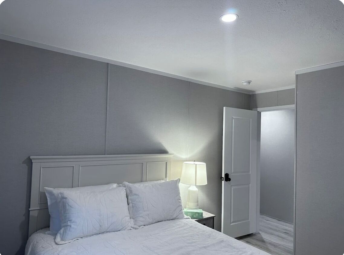 Une chambre à coucher avec un lit, une table de chevet avec une lampe et une porte.