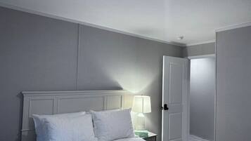 Une chambre à coucher avec un lit, une table de chevet avec une lampe et une porte.