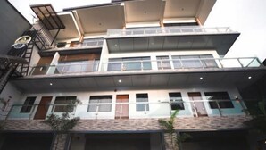 Un edificio de varios pisos con un diseño arquitectónico moderno, que cuenta con balcones, ventanas amplias y una entrada de garage.