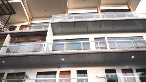 Un edificio de varios pisos con un diseño arquitectónico moderno, con balcones y grandes ventanales.