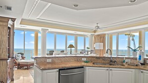 A spacious kitchen with a large island, white cabinetry, and a view of the ocean. - La Playa 703 (Pensacola)