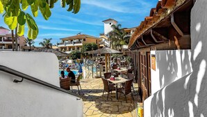 A courtyard with outdoor seating, a pool, and buildings with balconies. - Apartment in Golf del Sur with heated pool (Golf del Sur)