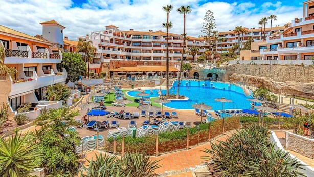A resort with multiple swimming pools, a large central pool, and a variety of sun loungers and umbrellas. - Apartment in Golf del Sur with heated pool (Golf del Sur)