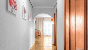 A hallway with a wooden door, a dining area with a table and chairs, and framed artwork on the walls. - Apartment in Golf del Sur with heated pool (Golf del Sur)