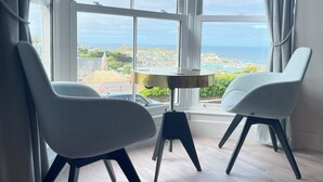 A room with two chairs facing a large window overlooking a coastal town. - Stunning iconic harbour & sea views of St Ives, parking and 2 mins walk to town (St Ives)