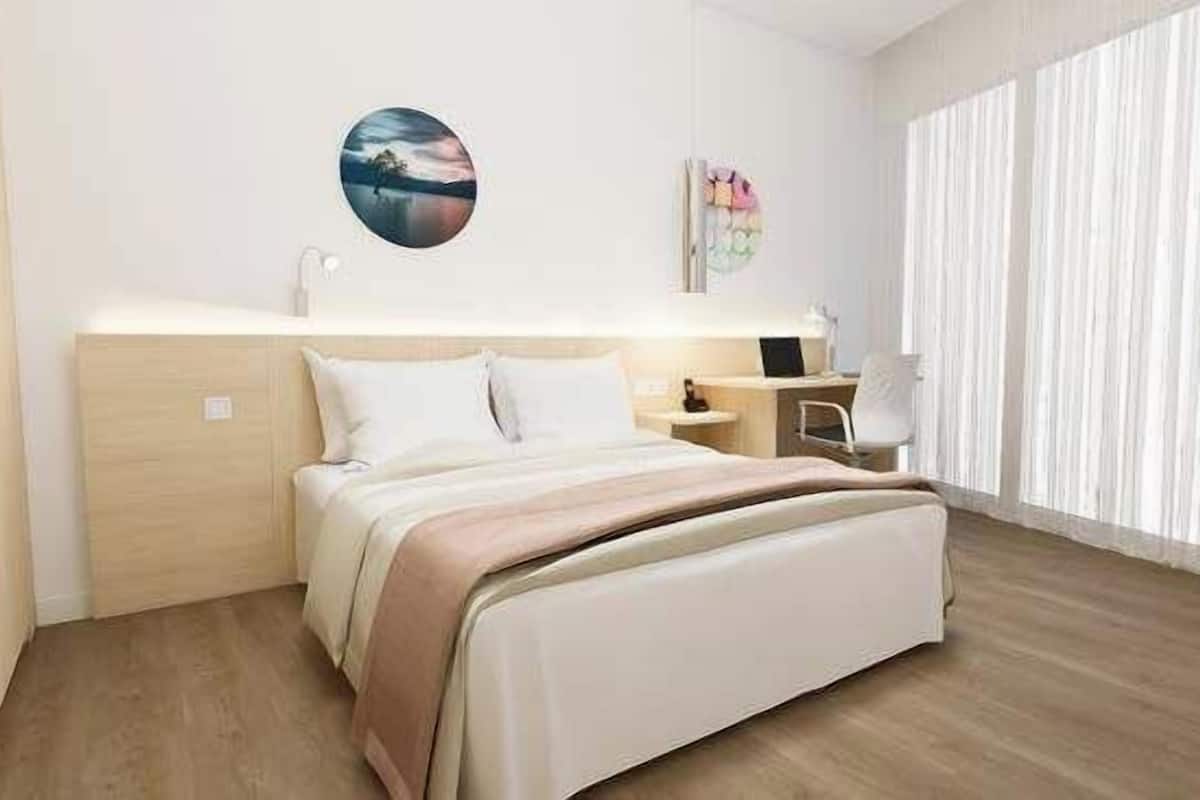 A modern bedroom with a bed, bedside table, lamp, and artwork on the wall.