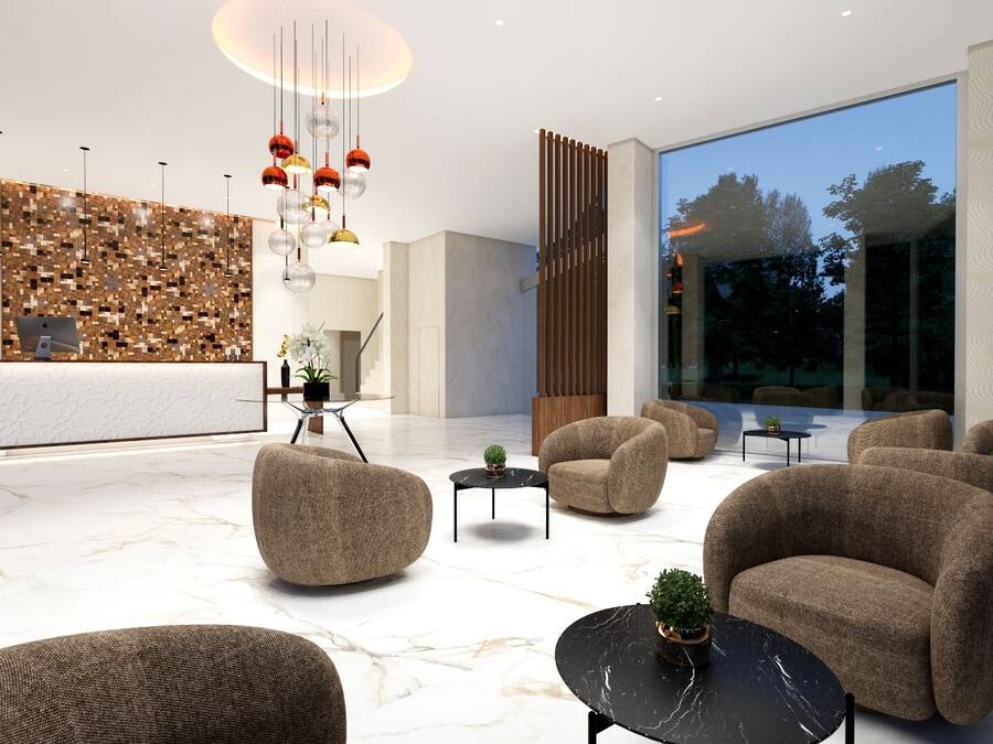A modern lobby with a reception desk, seating area, and large windows.