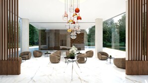 A modern lobby with a marble floor, seating area with sofas, a central plant, and a hanging light fixture. - SH Campus Lyceum (Moncada)