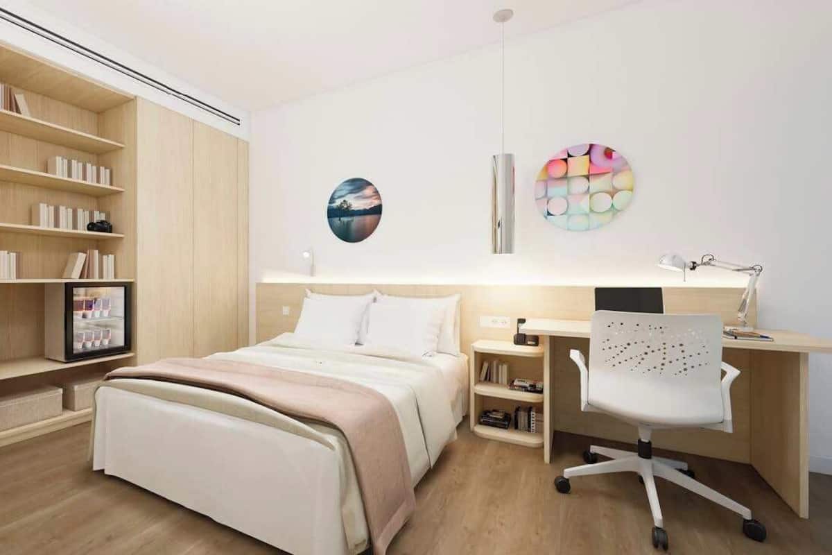 A modern bedroom with a bed, a desk, and a bookshelf.