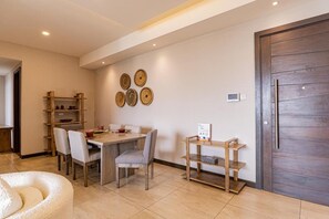 A dining area with a wooden table, chairs, and a small wooden shelf.