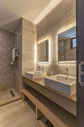 A modern bathroom with two sinks, a shower, and a bench.