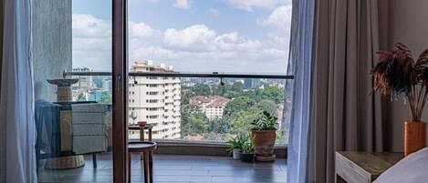 A bedroom with a large window overlooking a cityscape.