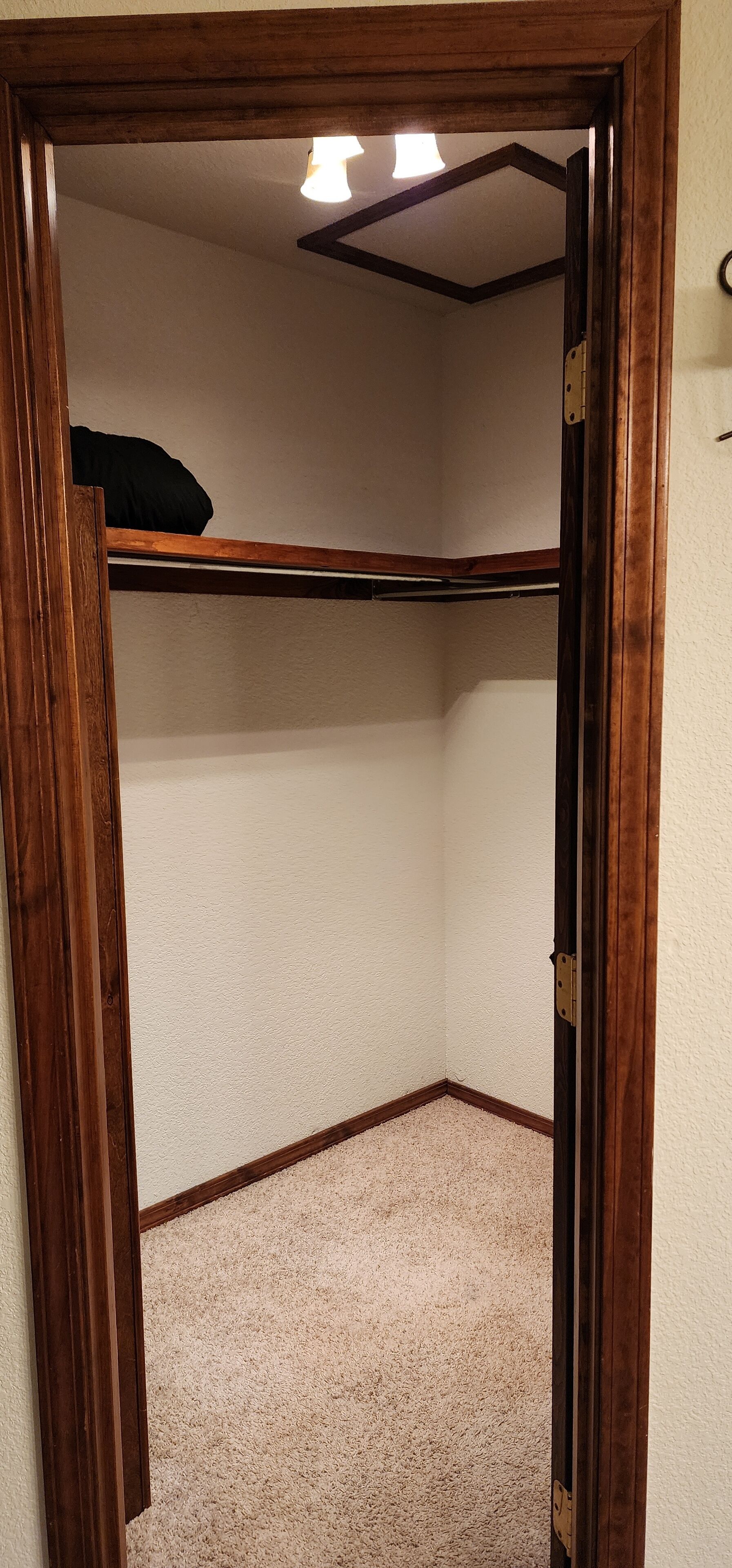 Une pièce dotée d’un cadre de porte en bois, d’un luminaire au plafond et d’un sol recouvert d’une moquette.