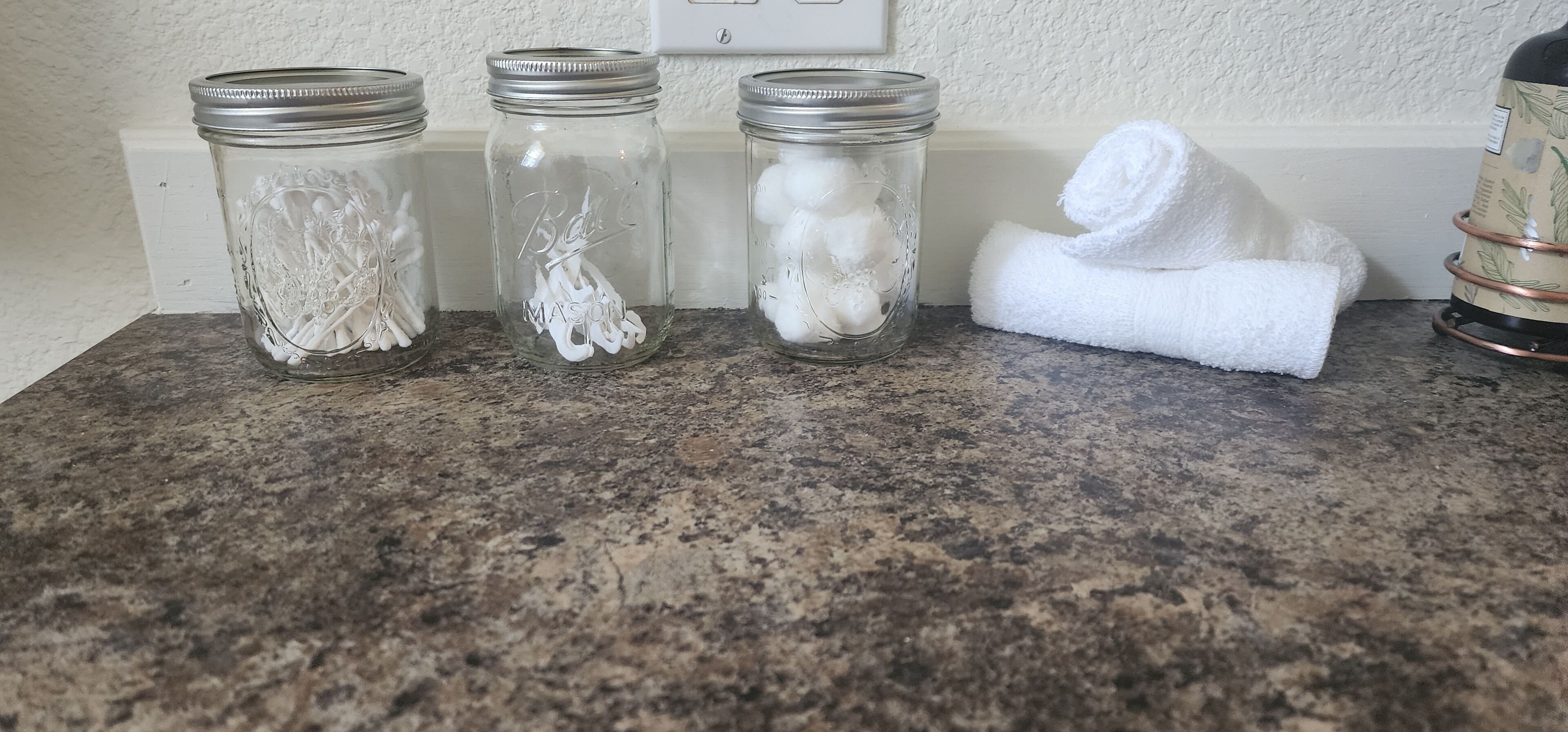 Three glass jars with metal lids on a granite countertop.