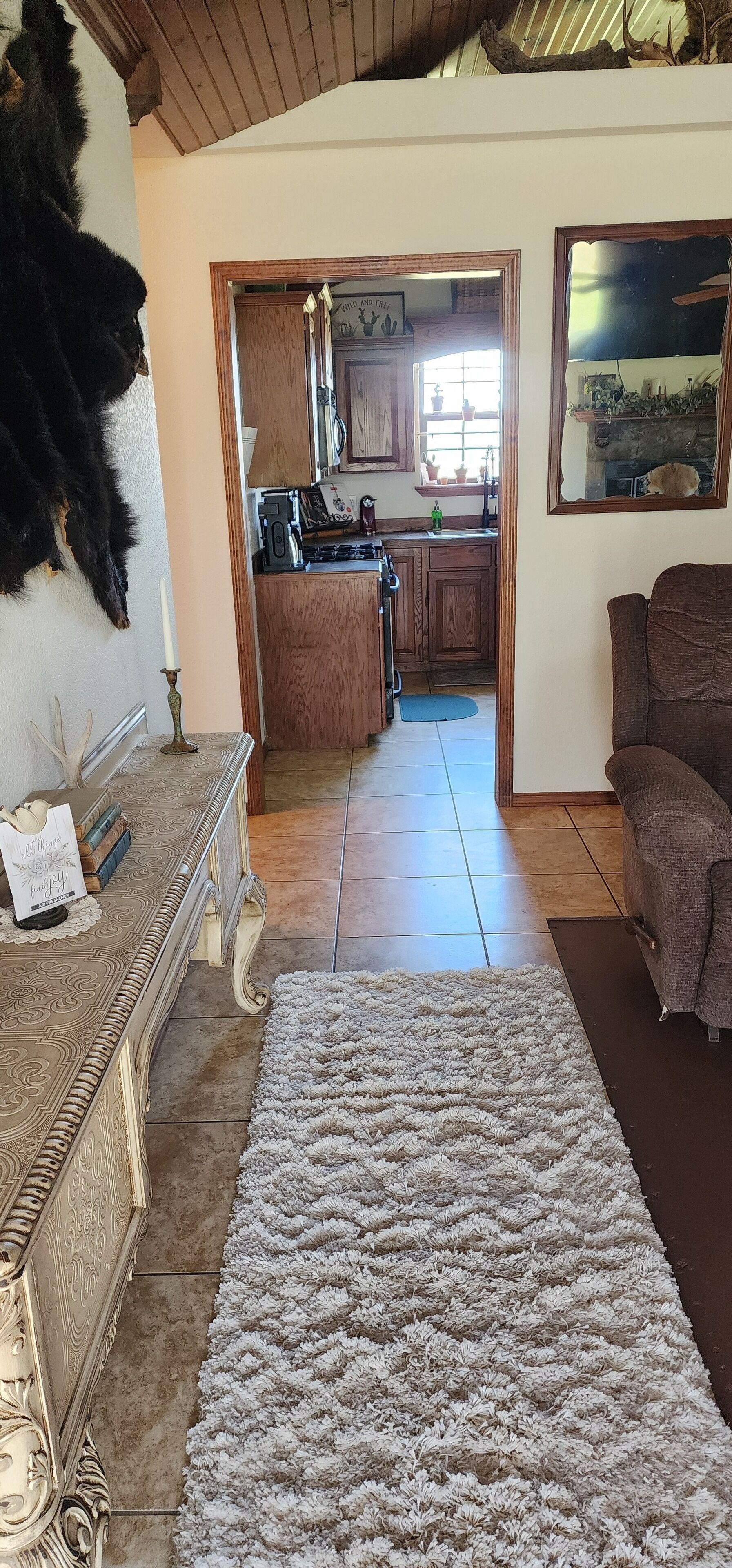 A living room with a large, patterned rug, a sofa, and a decorative fireplace.