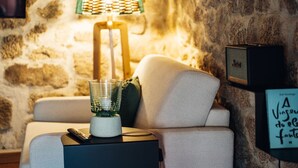A cozy room with a stone wall, a modern lamp, a small table with a glass container, and a framed quote on the wall. - a cosy contemporary one-bedroom studio unit with 31 m2 (Sortelha)