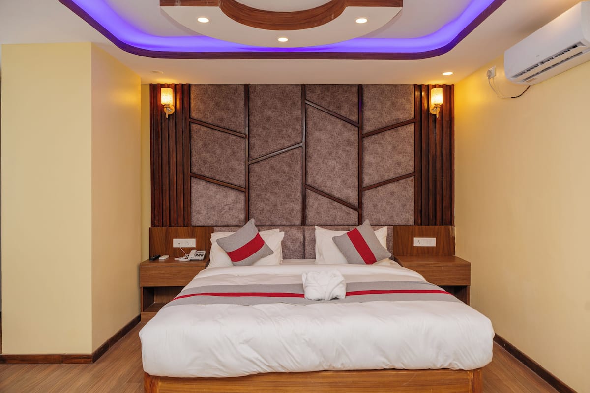 A hotel room with a large bed, wooden headboard, and a modern ceiling design.