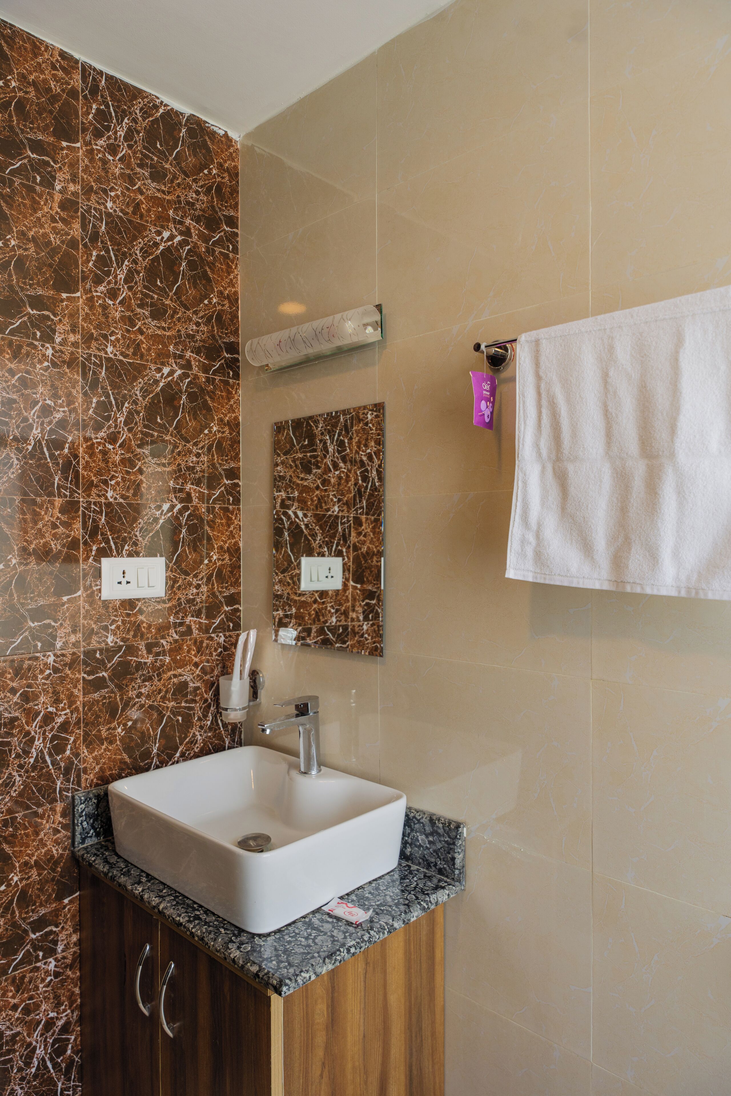 A bathroom with a marble vanity, a sink, a mirror, and a towel hanging on the wall.