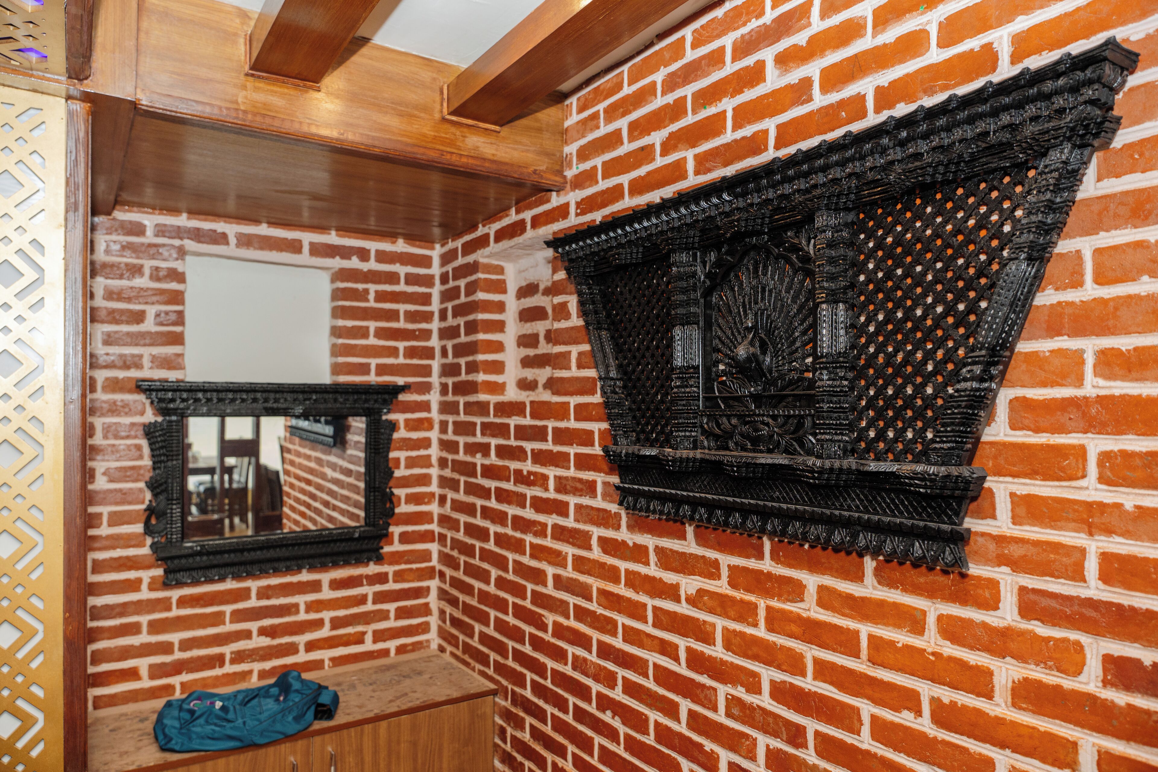 A room with a brick wall, a wooden ceiling, a mirror, and a shelf with a jacket.