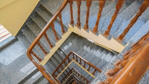 A multi-level wooden staircase with a handrail and a carpeted landing. - Hotel Royal Airport (Kathmandu)