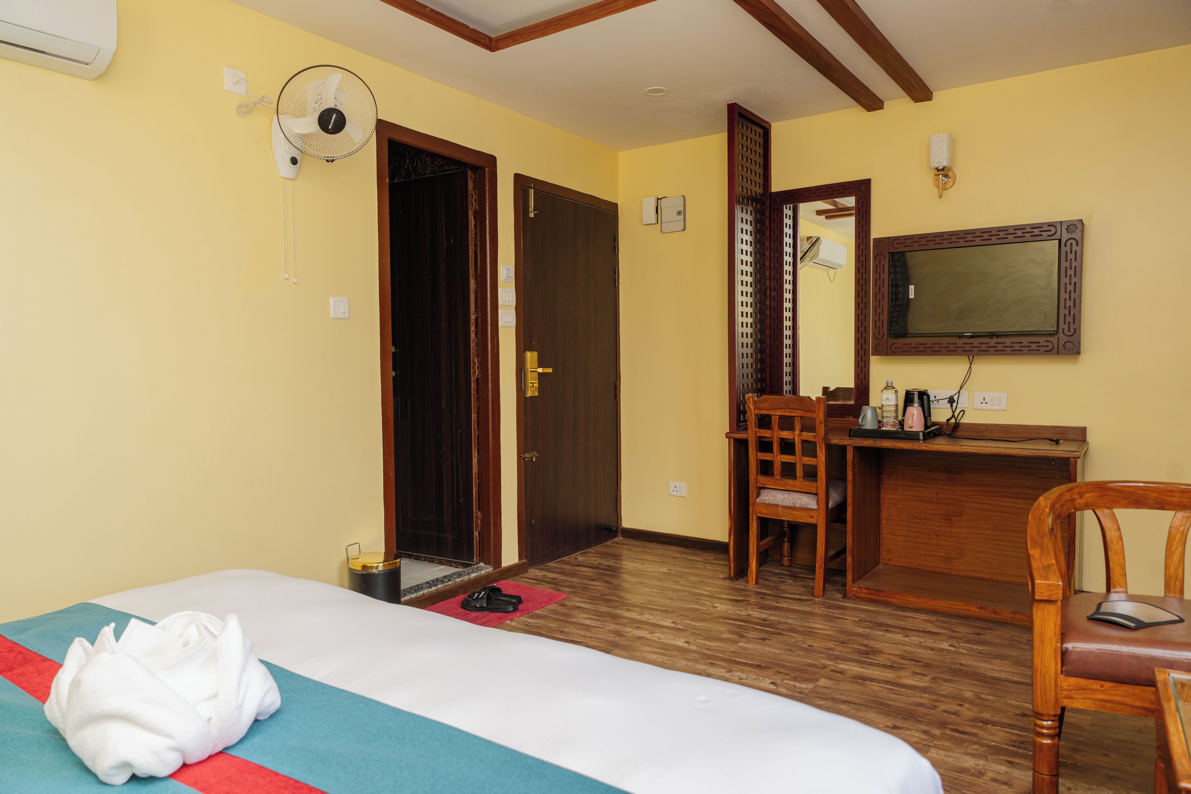 Una habitación de hotel con una cama, un escritorio, una silla, un televisor y una puerta.