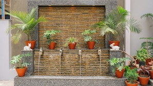 A stone wall with a water feature and potted plants. - Hotel Royal Airport (Kathmandu)