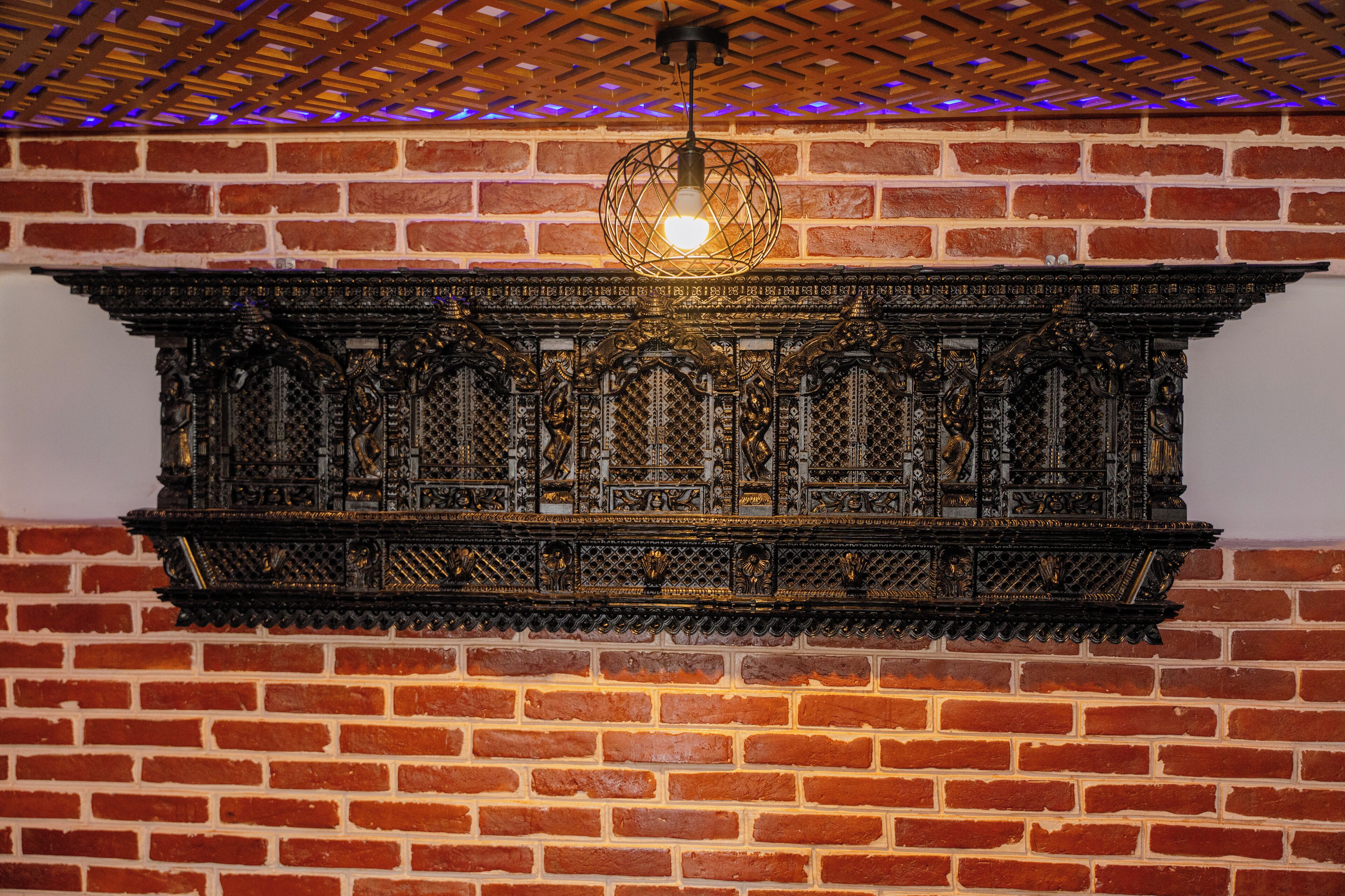 A brick wall with a decorative metal panel and a hanging light fixture.