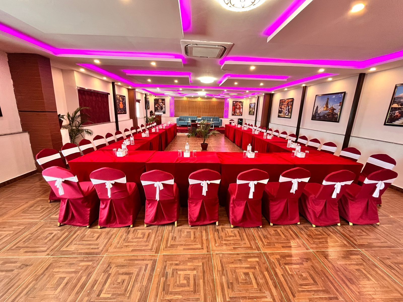 A conference room with a long table, red chairs with white sashes, and a wooden floor.