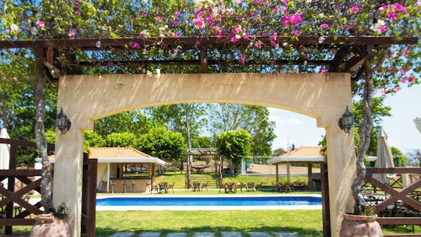 A covered outdoor area with a pool, surrounded by a wooden fence and potted plants. - Pocri Country Resort  (Pocrí)