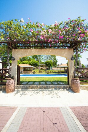 A covered outdoor area with a pool, surrounded by a wooden fence and potted plants.