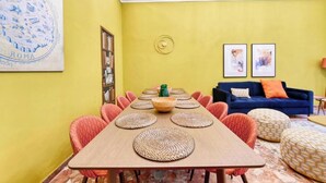 A dining area with a long table, multiple chairs, and a blue sofa in the background. - Elegant Historic Apartment in Central Rome
 (Roma)