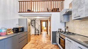A modern kitchen with a herringbone wood floor, grey cabinets, and a built-in gas stove. - Elegant Historic Apartment in Central Rome
 (Roma)