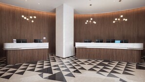 Un espace d’accueil comprenant deux comptoirs, un pilier central et un sol à motifs.