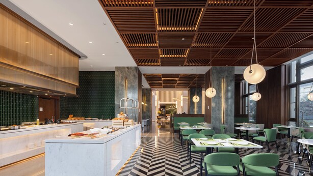 Un restaurant moderne doté d’un buffet central, de sièges verts et d’un sol à motifs.