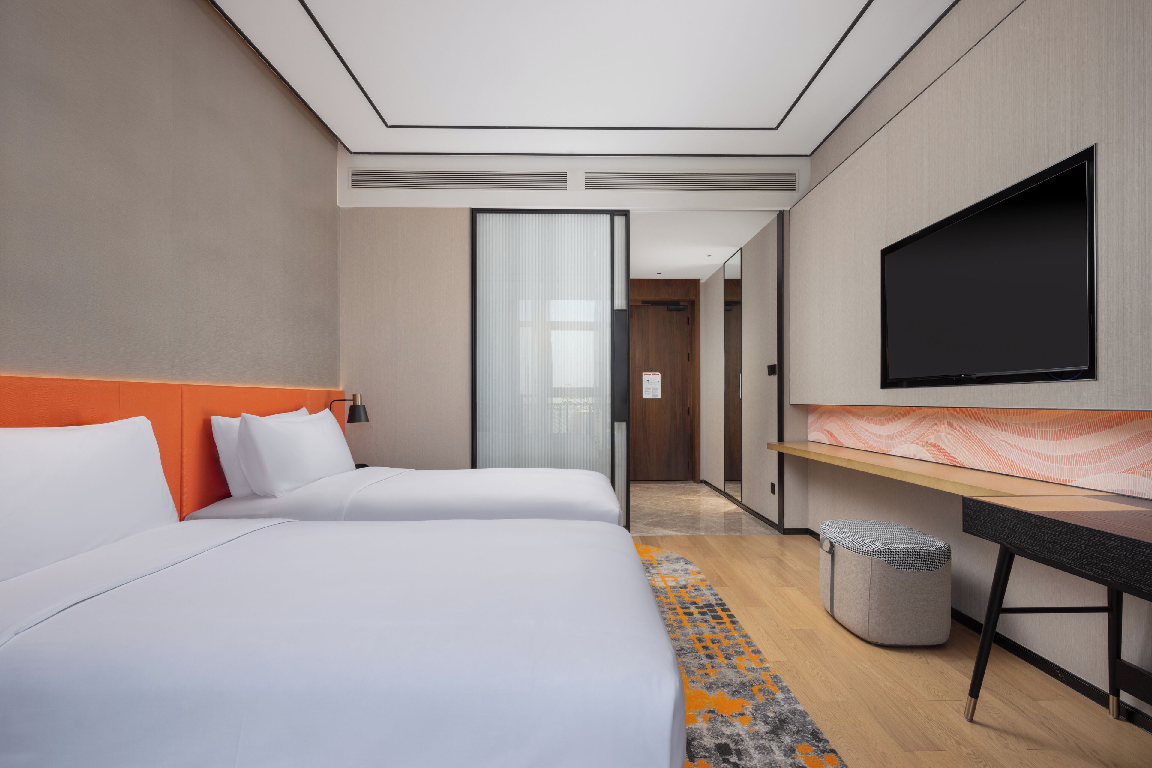 Habitación de hotel moderna con dos camas, un escritorio, un televisor y un cubo de basura.