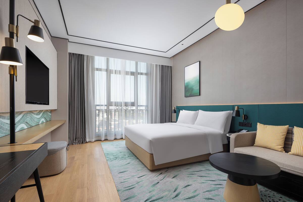 Una habitación de hotel moderna con cama, sofá, escritorio y televisor.