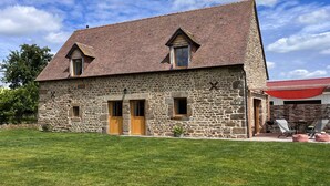 A stone house with a sloped roof, two windows, and a door.