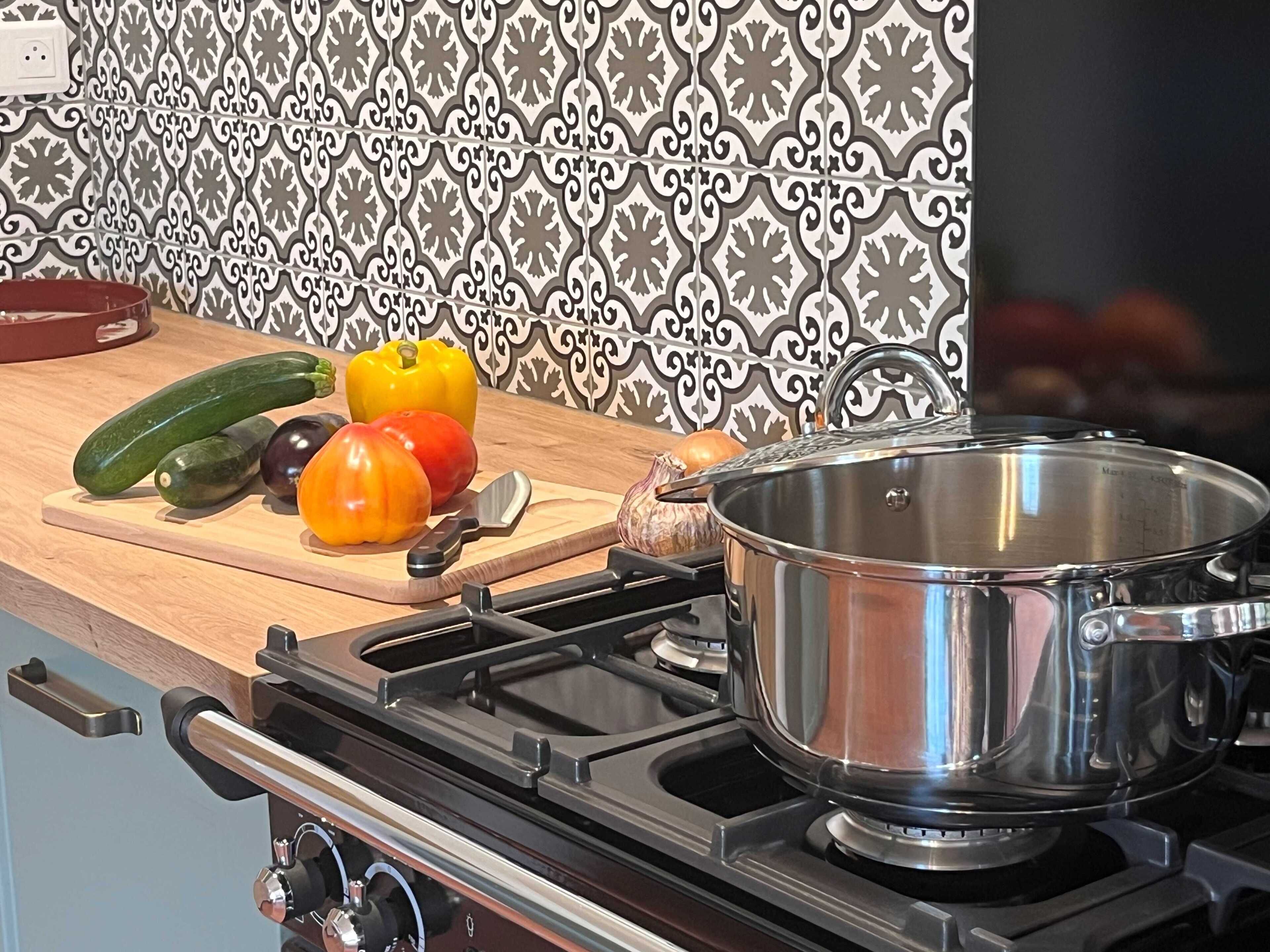 A kitchen with a stove, a pot, and various vegetables on a cutting board.