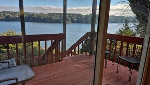 A wooden deck with a view of a lake and forest. - Waterfront charming 3-bedroom house with hot tub, sauna and bikes, sleeps 6 (Shelton)