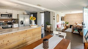 A modern kitchen with a wooden island, stainless steel appliances, and a dining area with a wooden table and chairs. - Modern Family Home in Laguna Beach! 4-block Walk to Beach + Pet Friendly! (Panama City Beach)