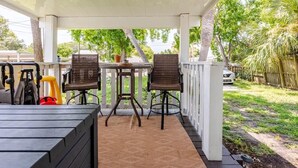 A covered patio with two wicker chairs, a table, and a black bench. - Modern Family Home in Laguna Beach! 4-block Walk to Beach + Pet Friendly! (Panama City Beach)