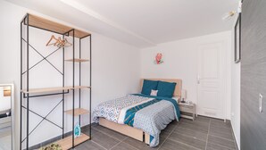 A bedroom with a bed, a wooden wardrobe, a nightstand, and a door.