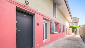 A residential building with a red facade, a grey door, and a small window.