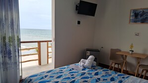 Habitación de hotel con cama, escritorio, silla, televisión y vista a la playa.