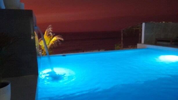 Una piscina con vistas al océano al atardecer.