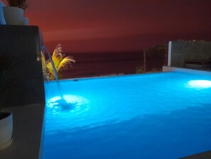 Une piscine avec vue sur l’océan au coucher du soleil.