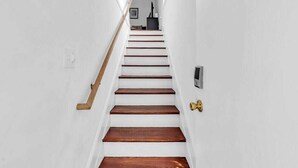 Una escalera de madera con barandilla de latón que conduce a un rellano con un objeto negro y un marco de fotos.