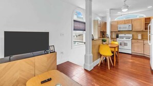 Una cocina moderna con armarios de madera, un microondas y un comedor con sillas amarillas.